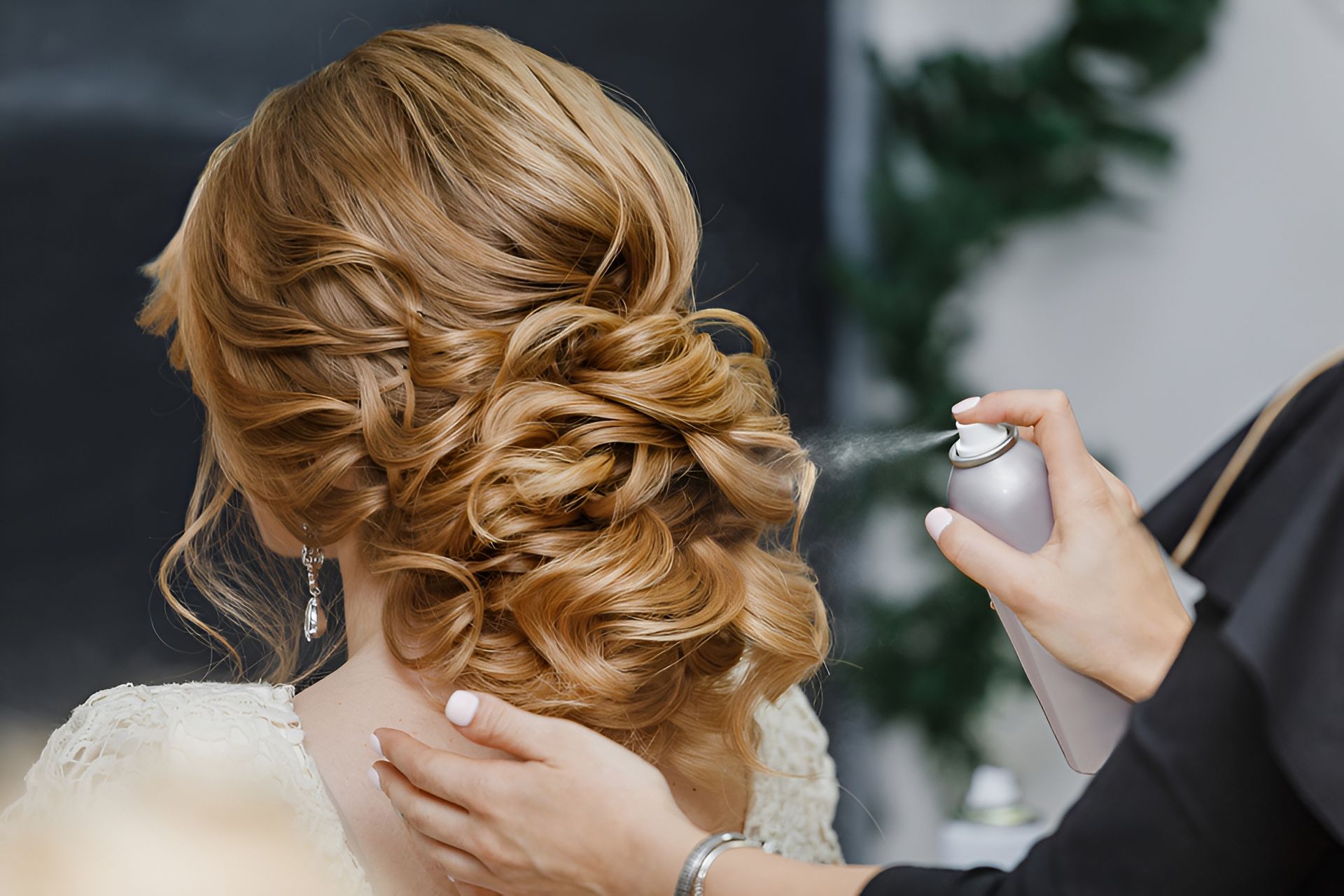 Stylist spraying hairspray on an updo hairstyle. — Wow! Excellence in Hair in Toowoomba, QLD