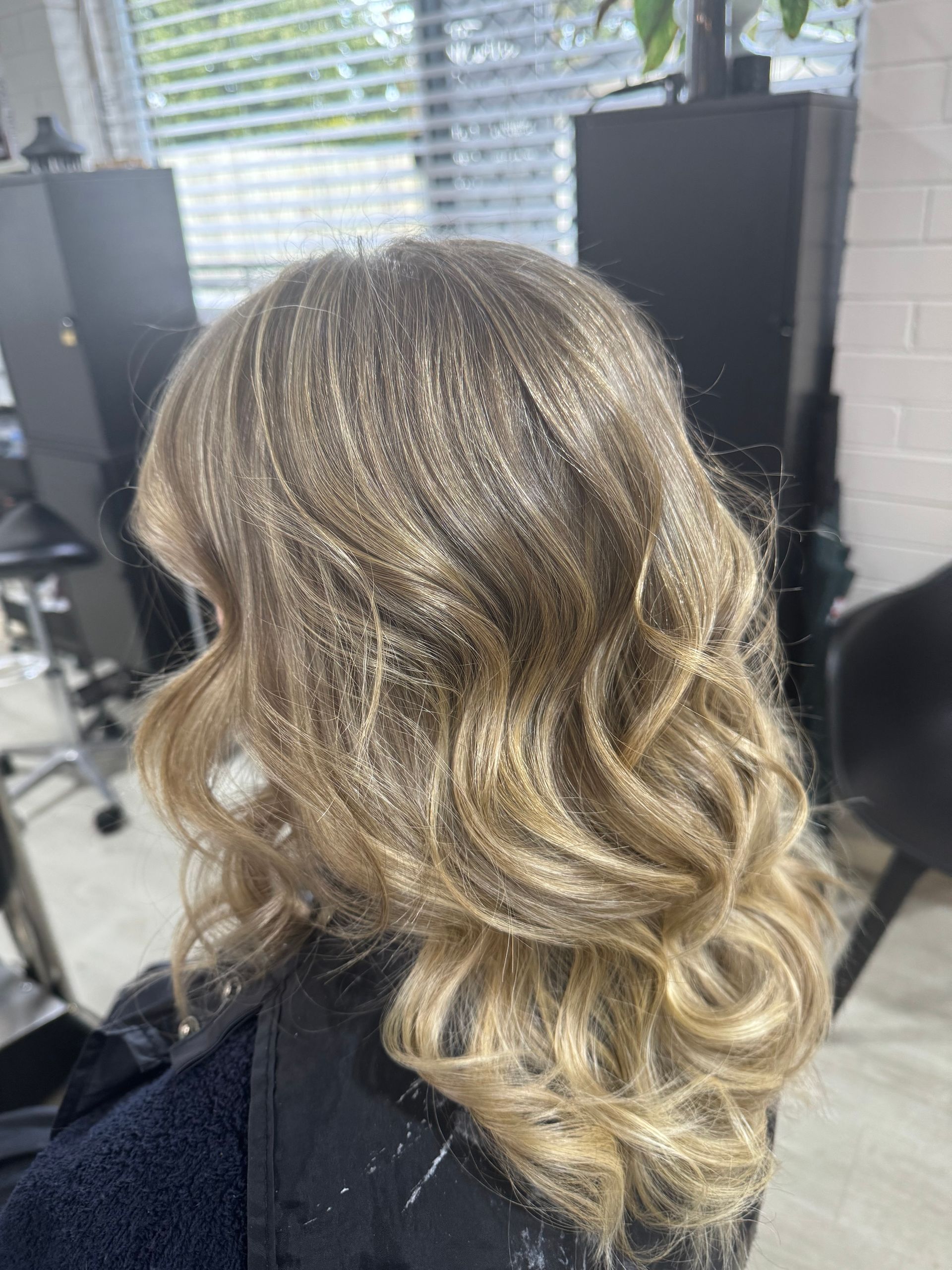 Woman with blonde, wavy hair in a salon setting.