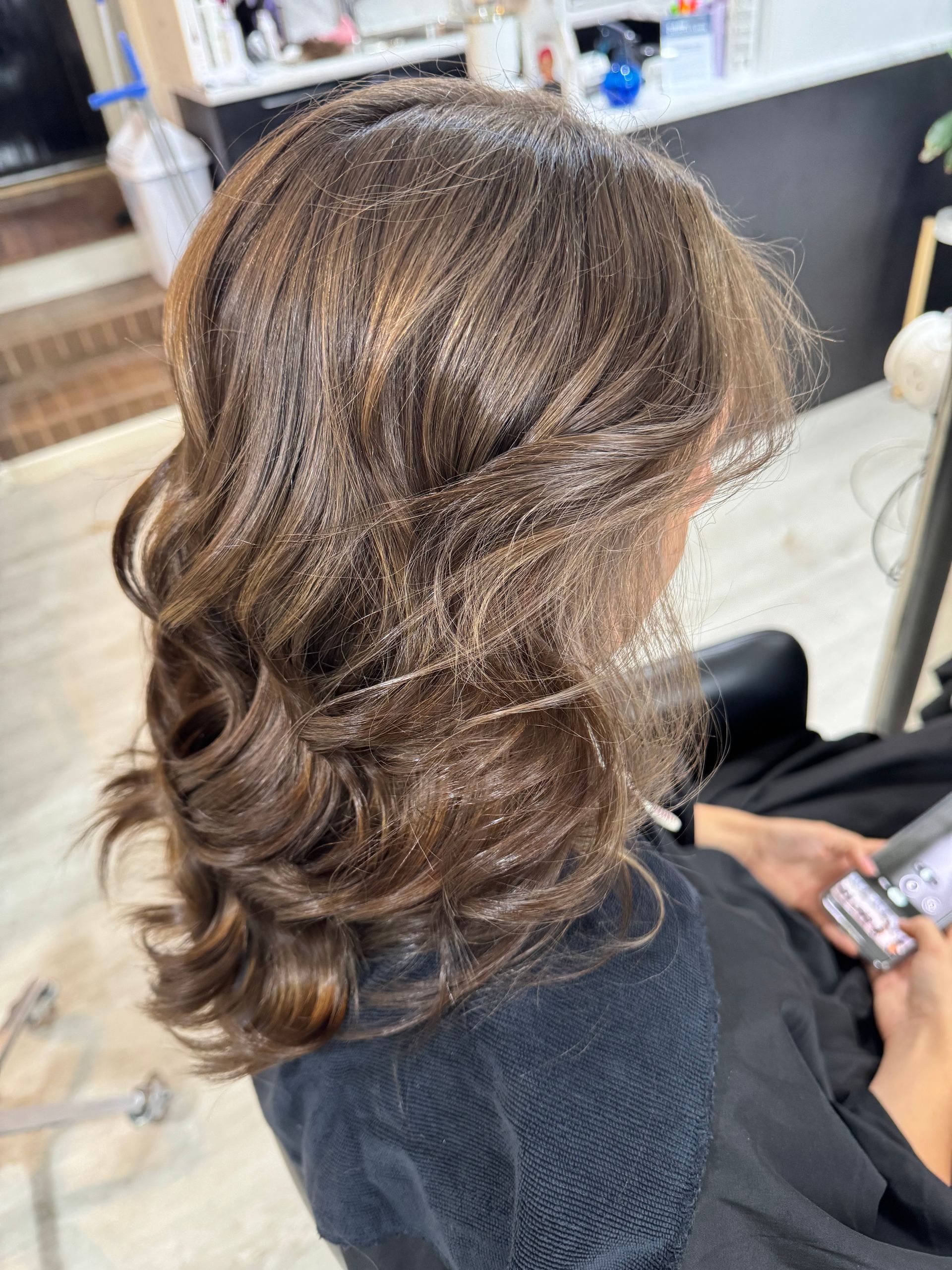 Woman with wavy brown hair, highlights, and salon setting.