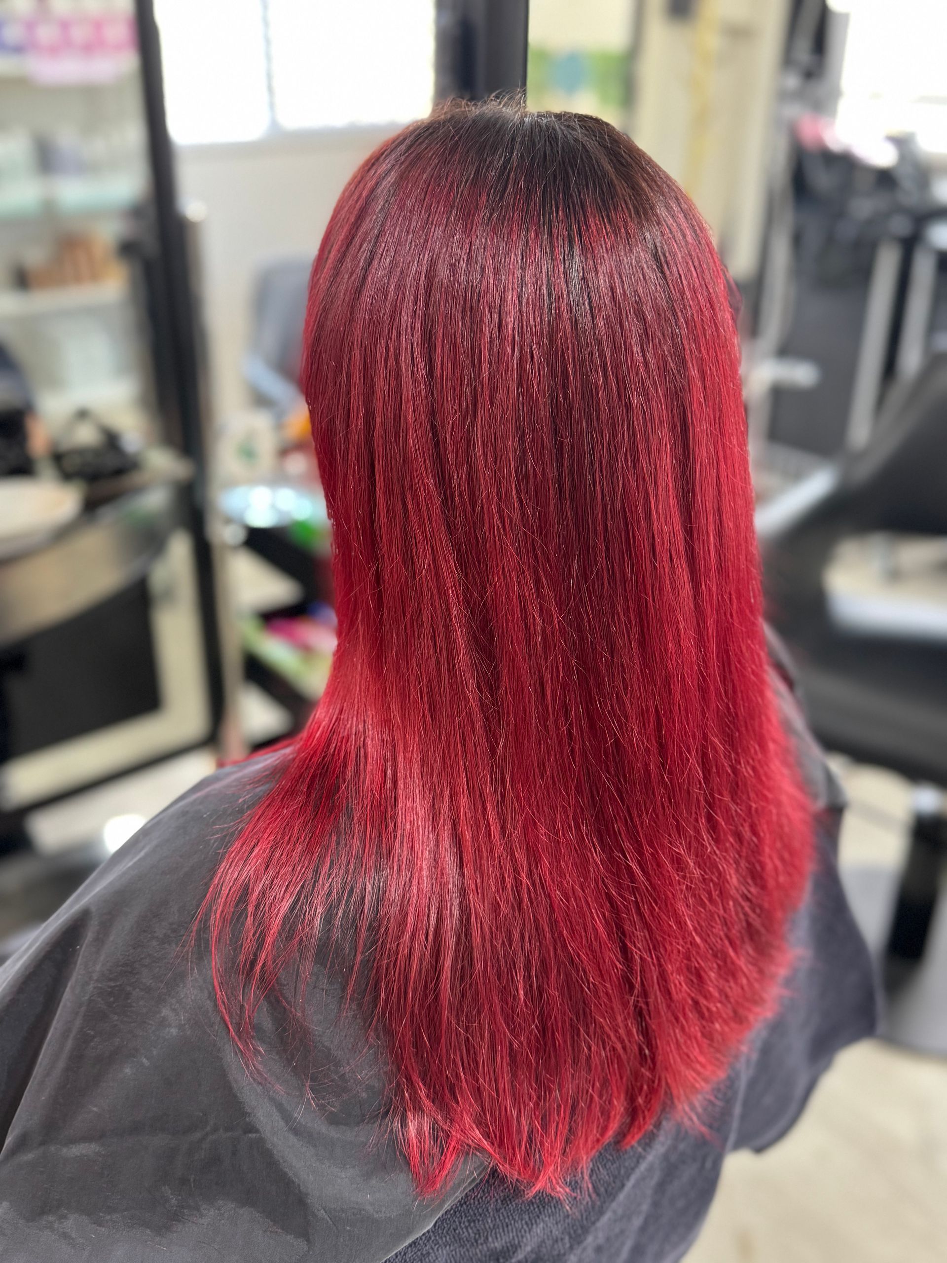 Red and black hair, styled straight, in a salon setting.