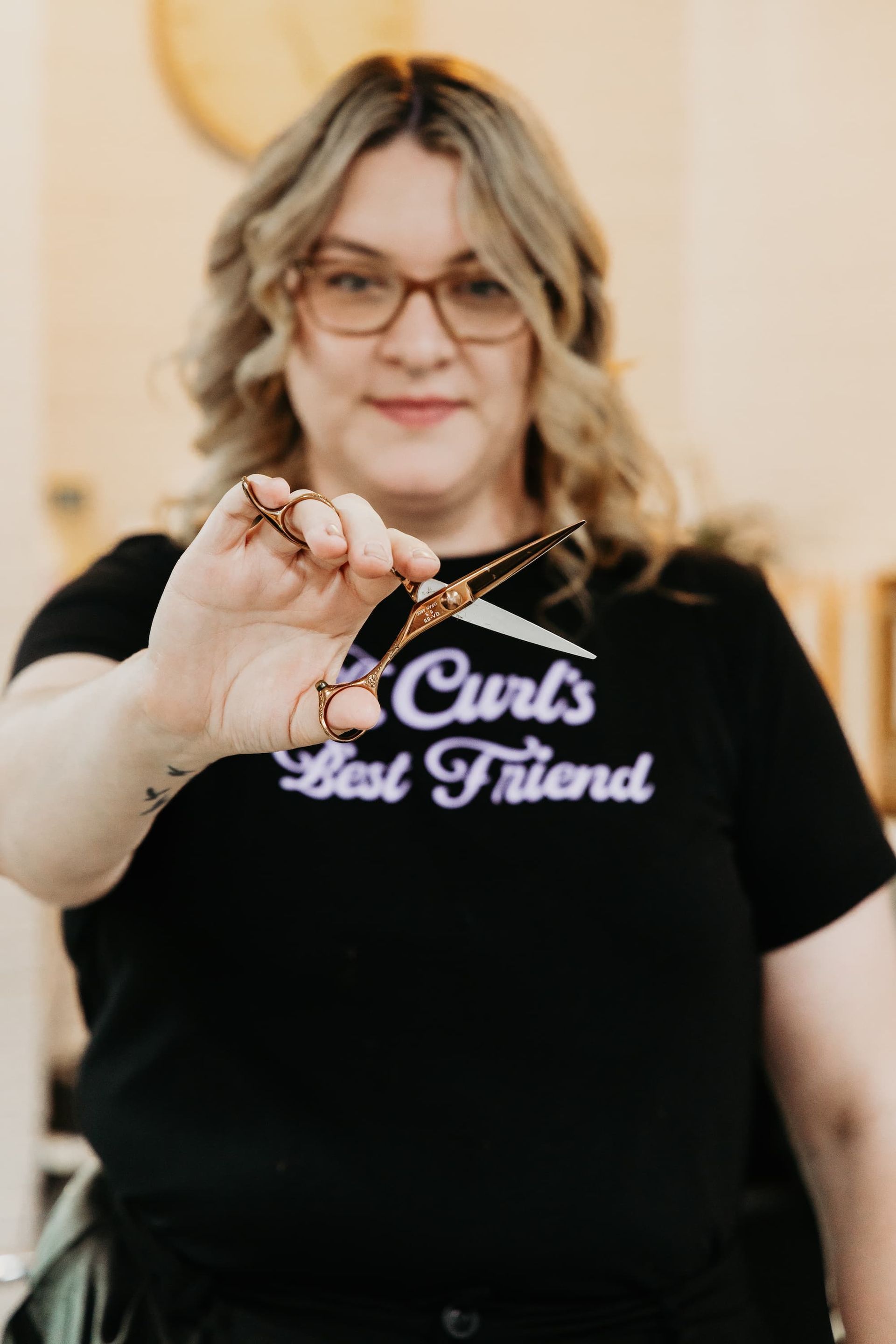 Person holding scissors; wearing glasses and a shirt that says 