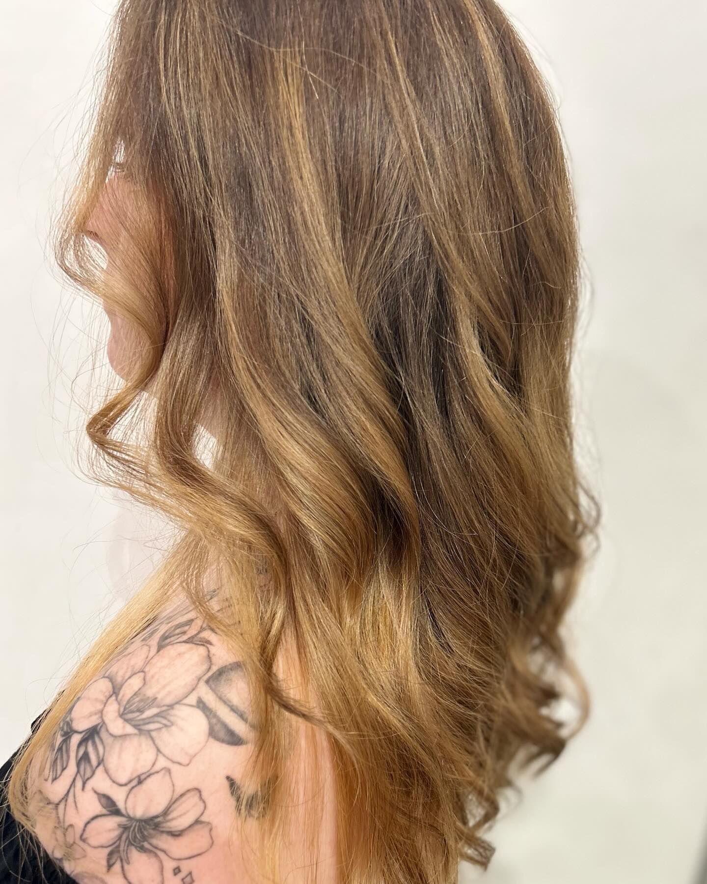 Woman with wavy, highlighted brown hair; a floral tattoo is visible on her shoulder — Wow! Excellence in Hair in Toowoomba, QLD