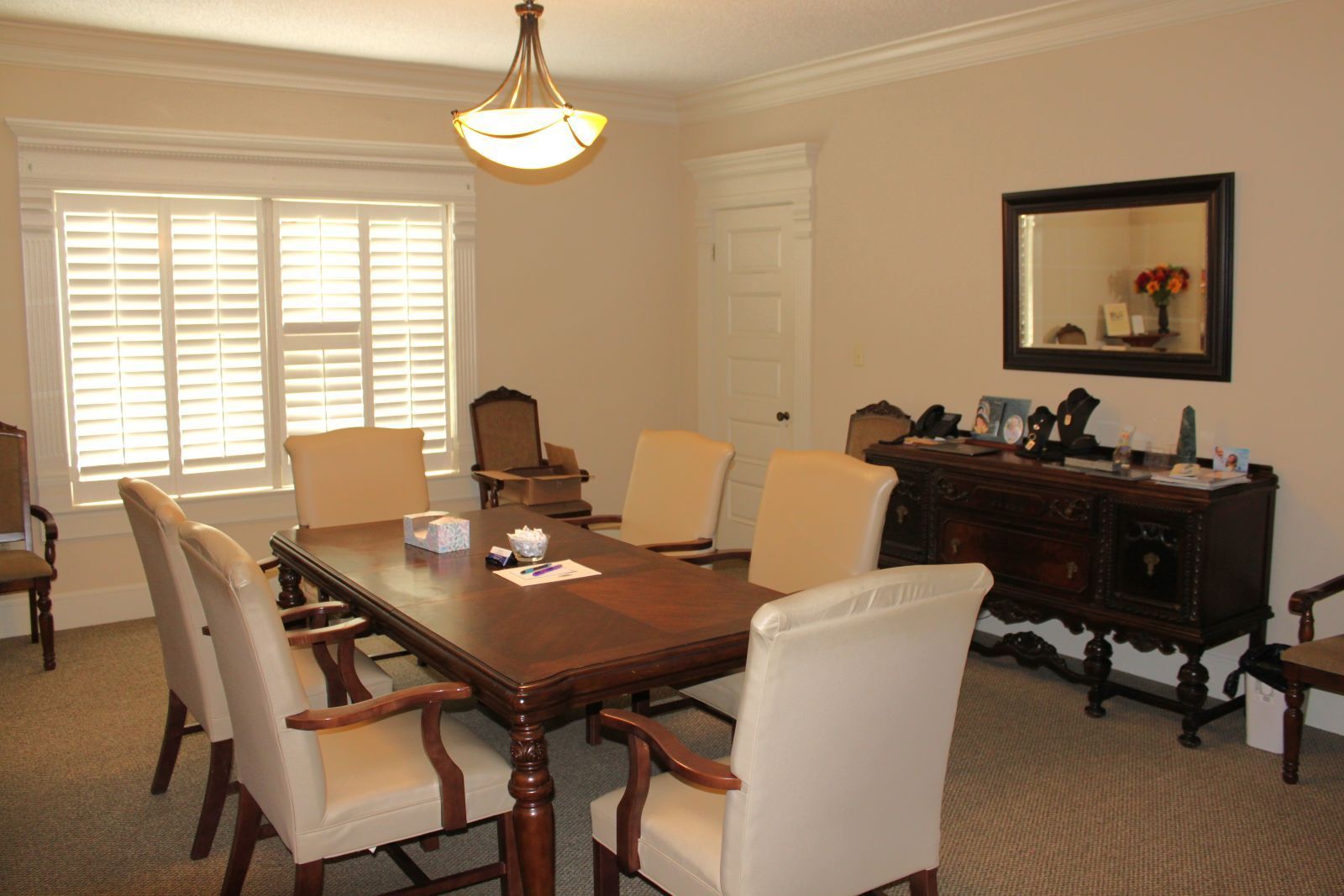 A dining room with a table and chairs and a mirror