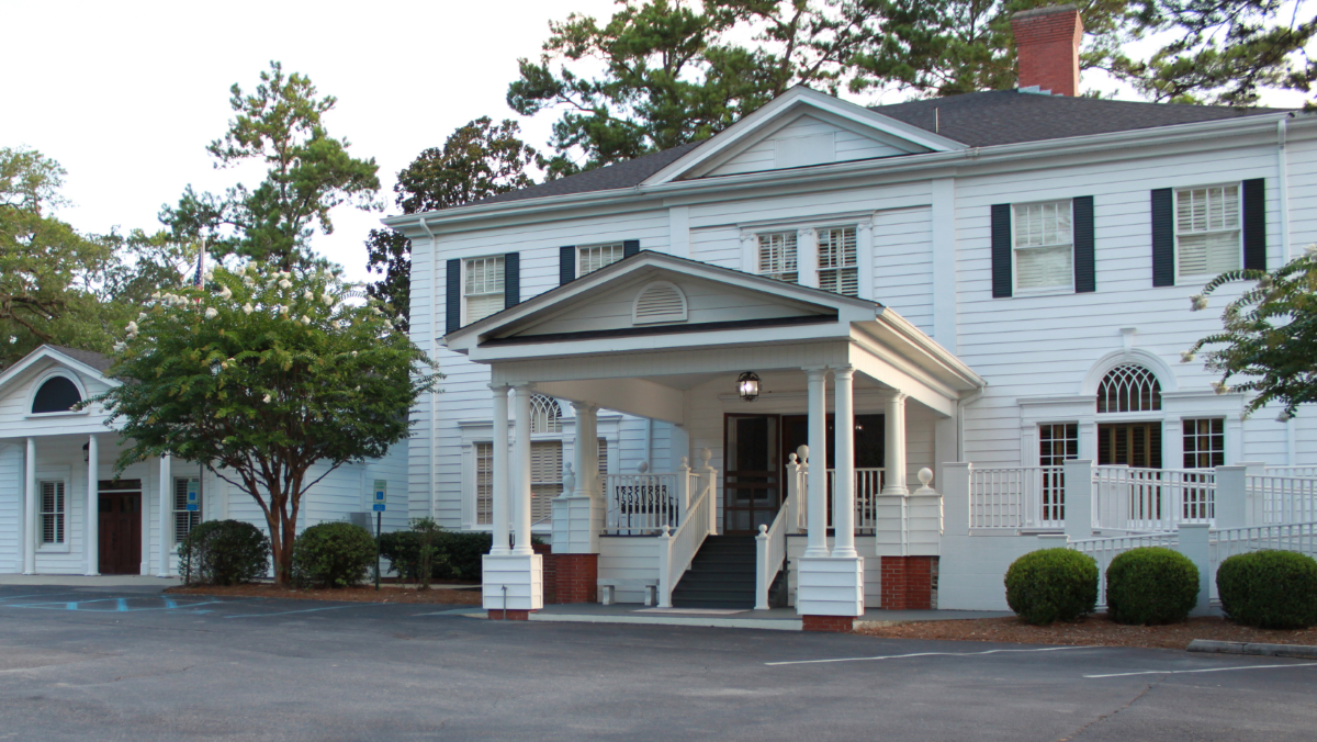 A large white house with a porch and trees in front of it