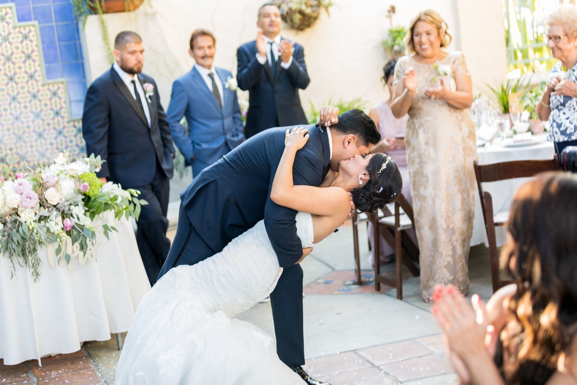 A bride and groom are kissing at their wedding reception.