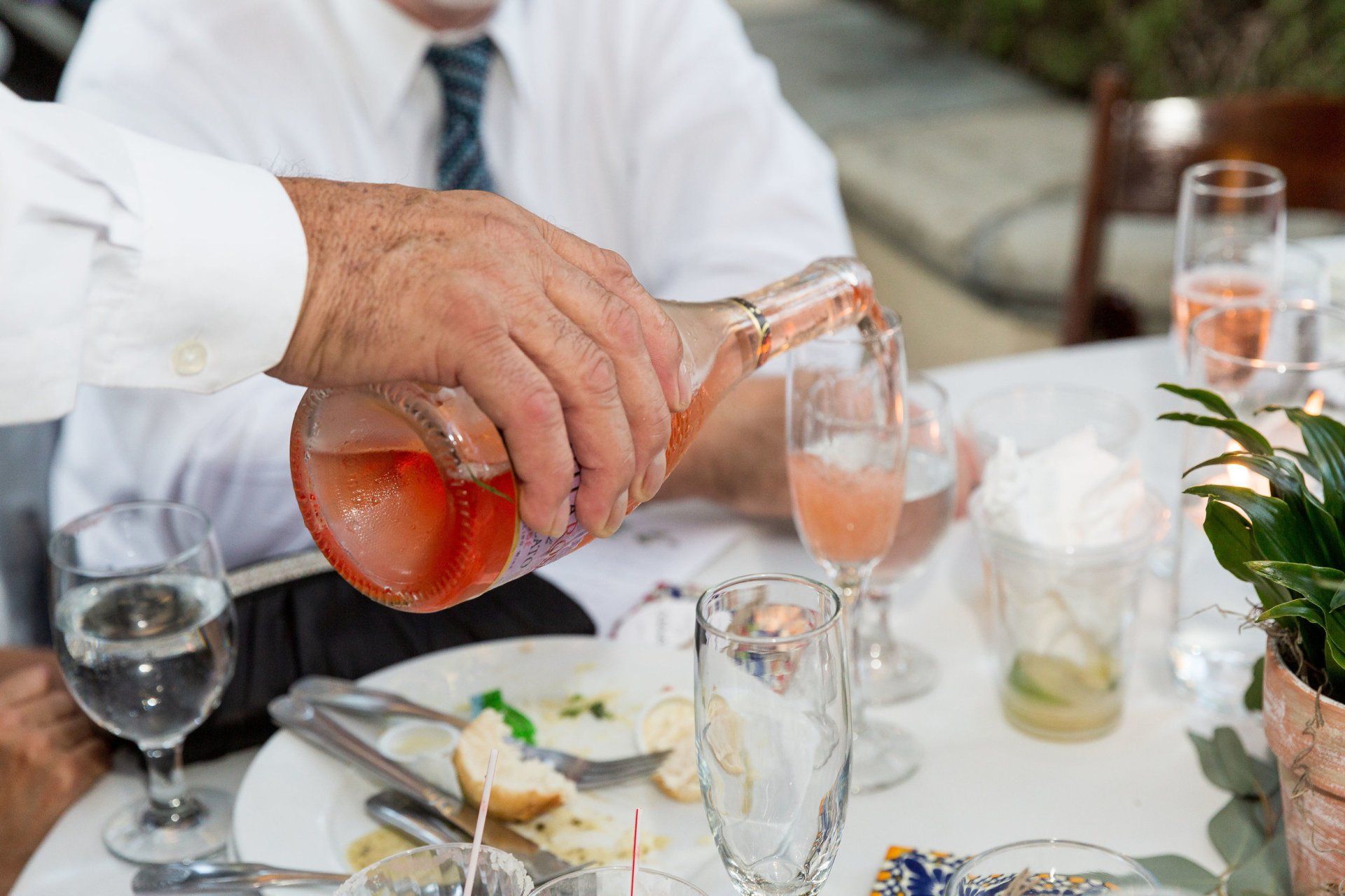 A man is pouring a drink into a glass at a table.