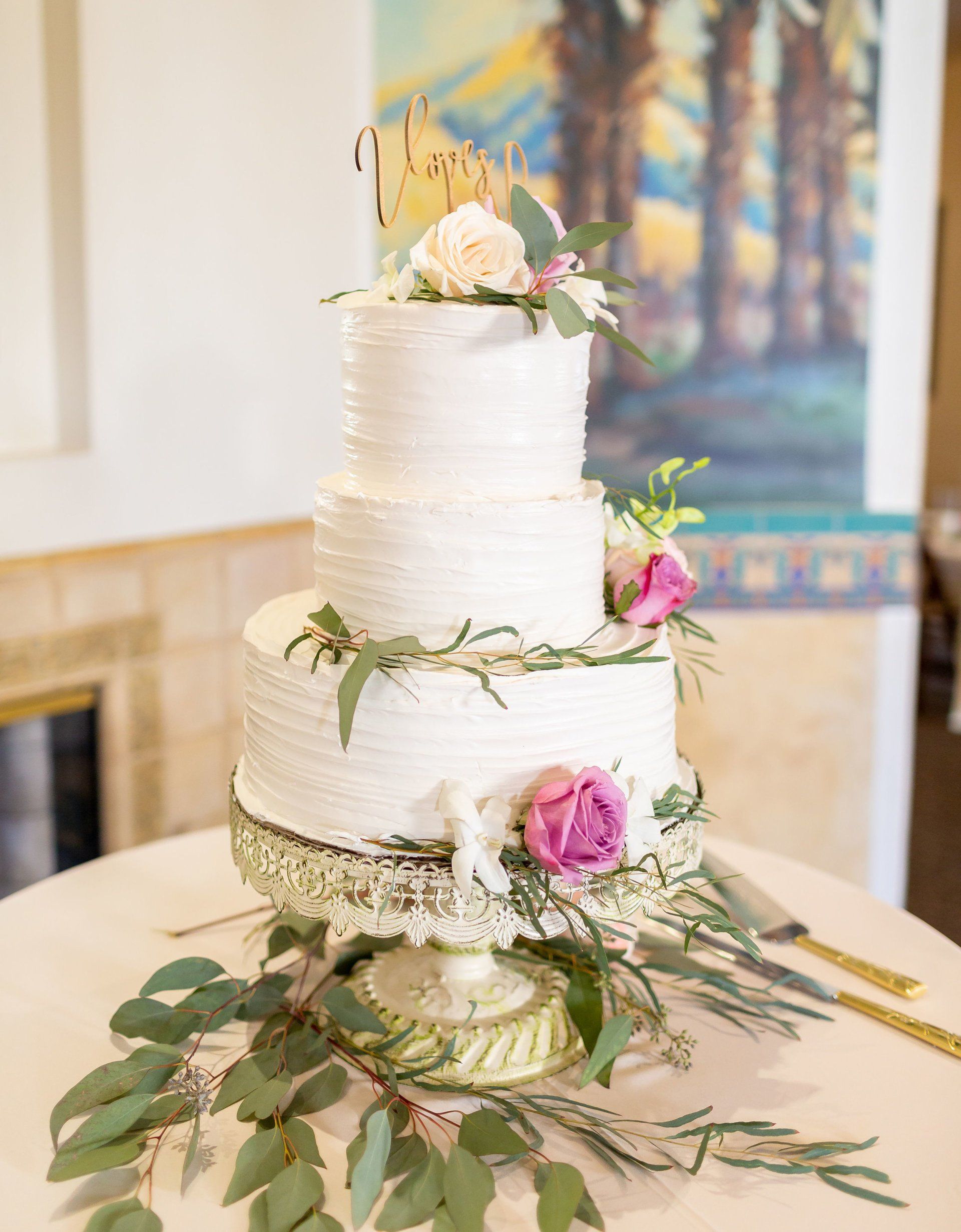 A white wedding cake is sitting on top of a white table.