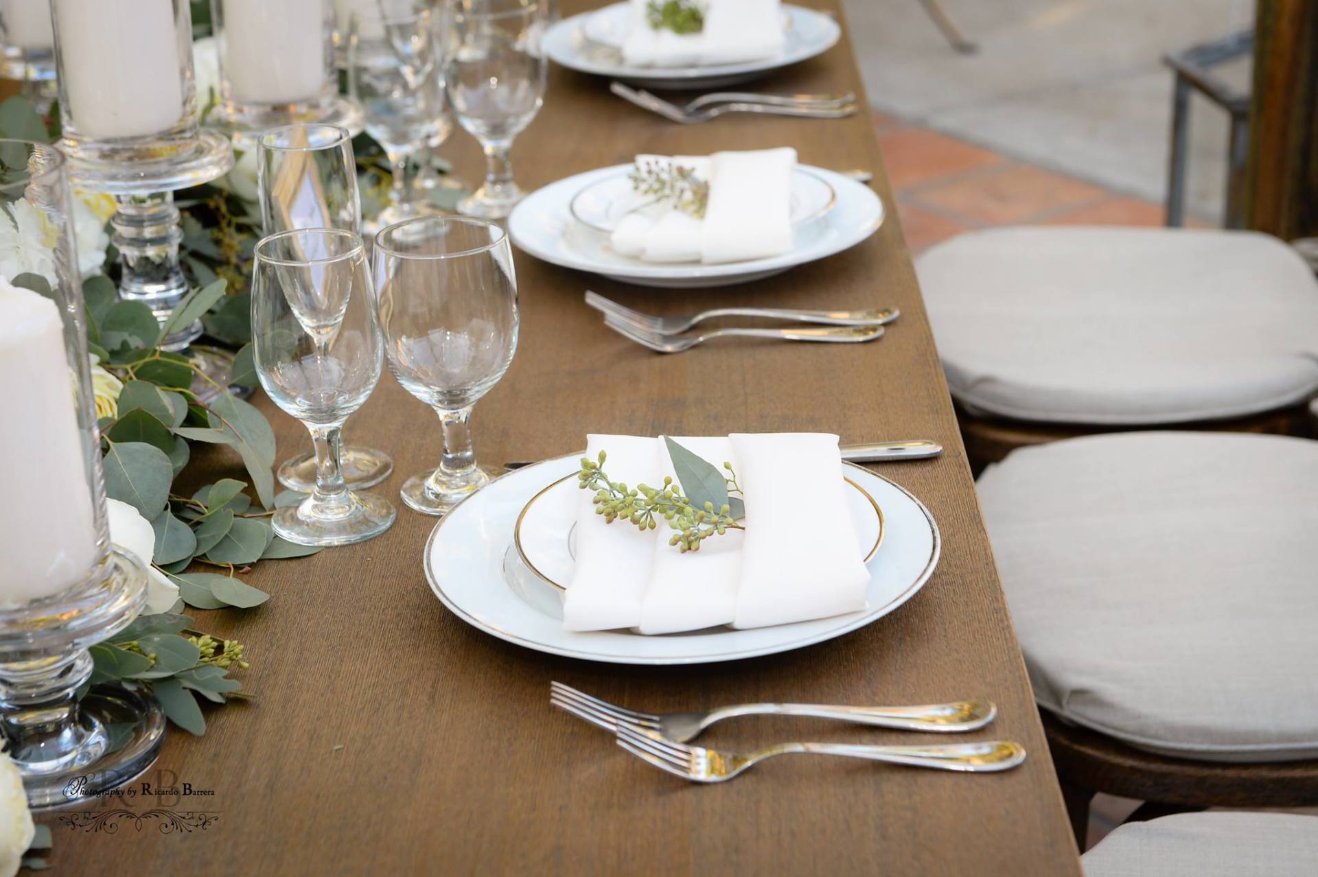 A long wooden table with plates , utensils , and candles on it.