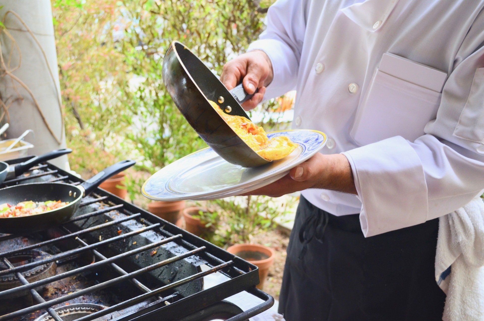 A chef is cooking food in a frying pan on a stove.