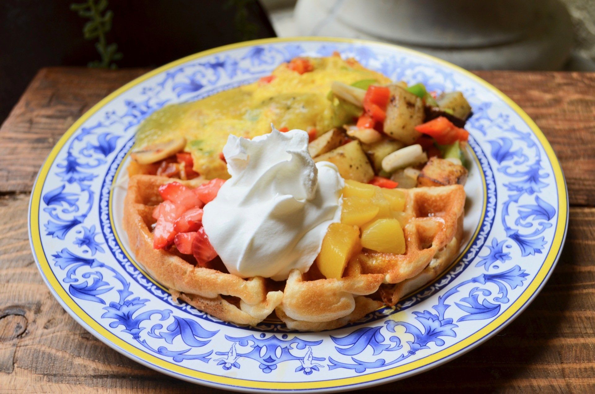 A blue and white plate topped with waffles and whipped cream.