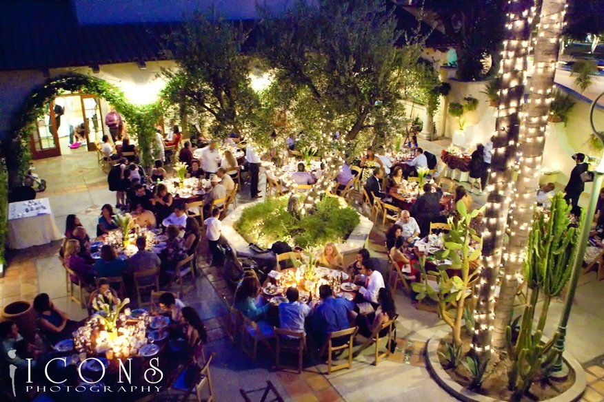 A group of people are sitting at tables in a courtyard with icons photography written on the bottom