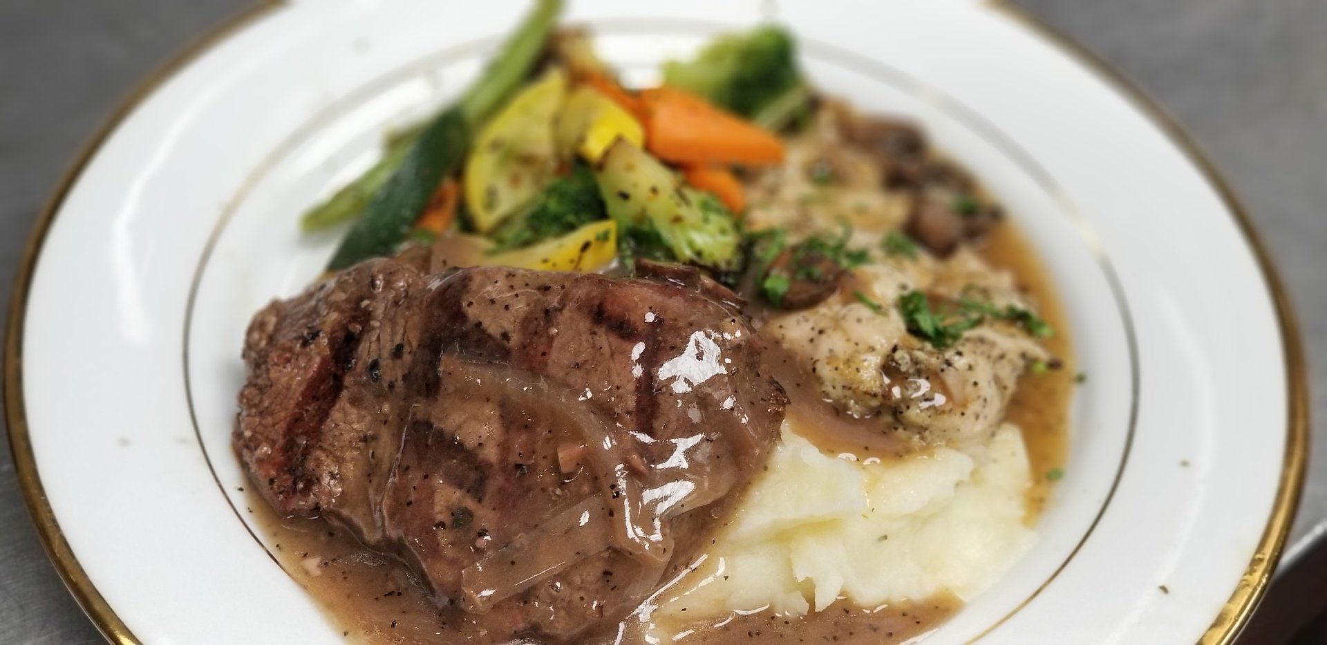 A white plate topped with meat , mashed potatoes and vegetables.