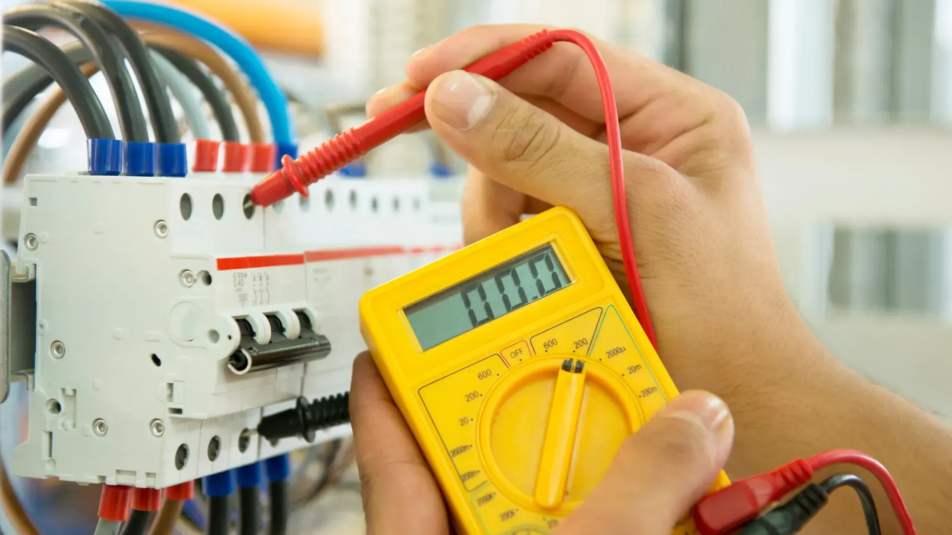 A person is using a digital multimeter to test an electrical circuit.