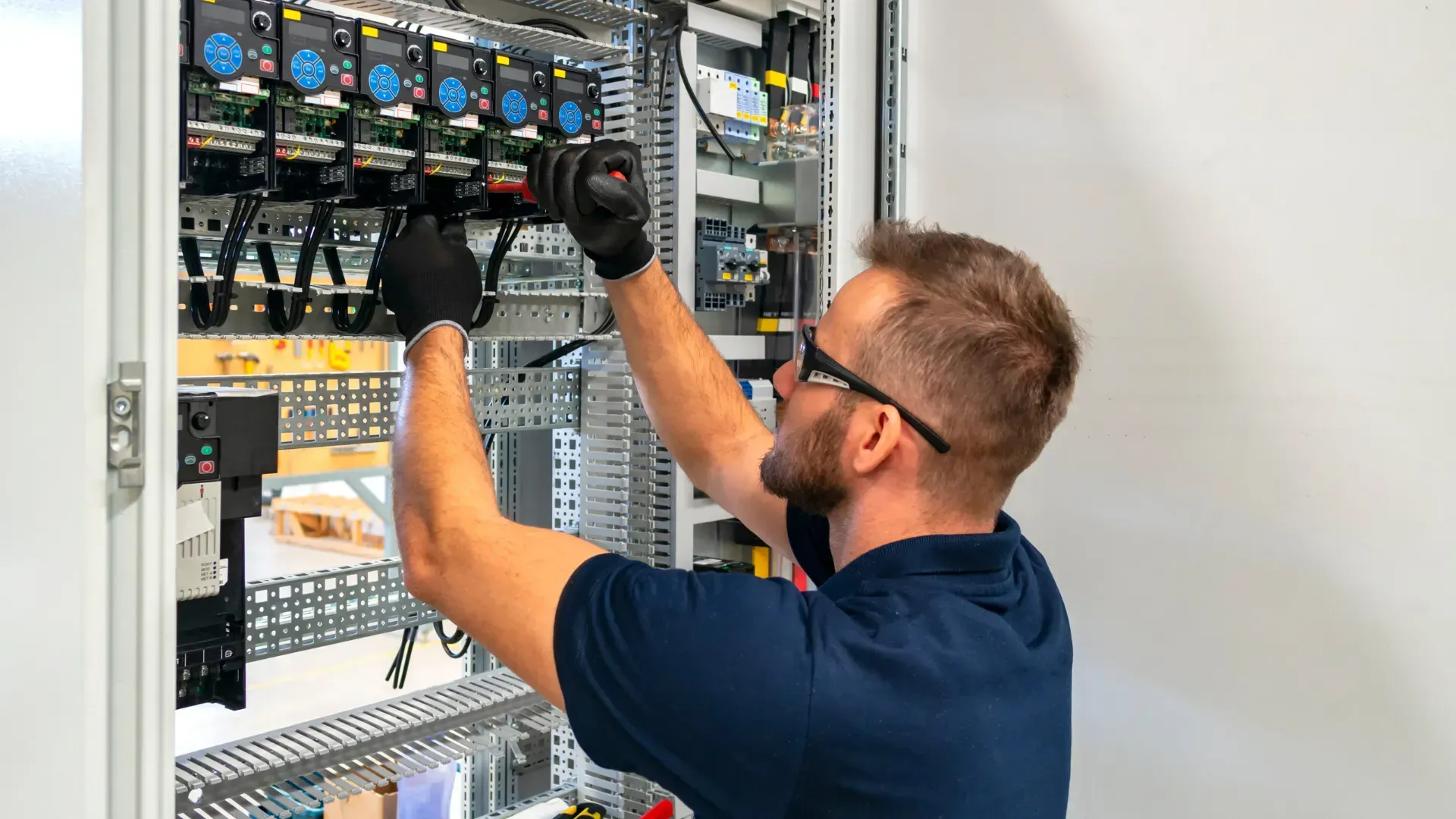 A man is working on a electrical panel with a screwdriver.