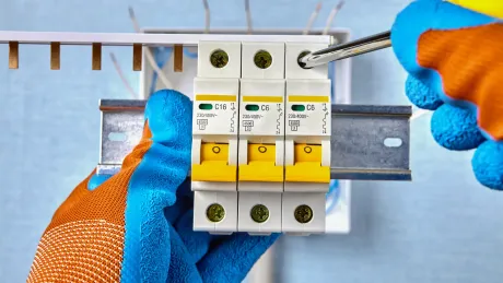 A person is holding a circuit breaker with a screwdriver.
