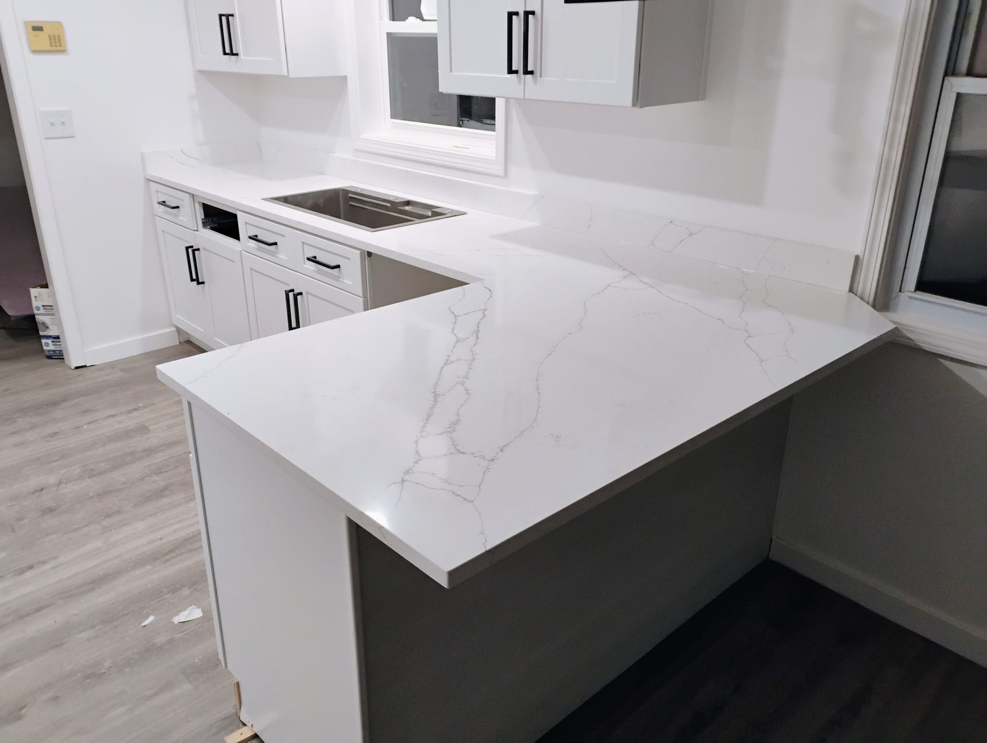 A kitchen with white cabinets and a white counter top.