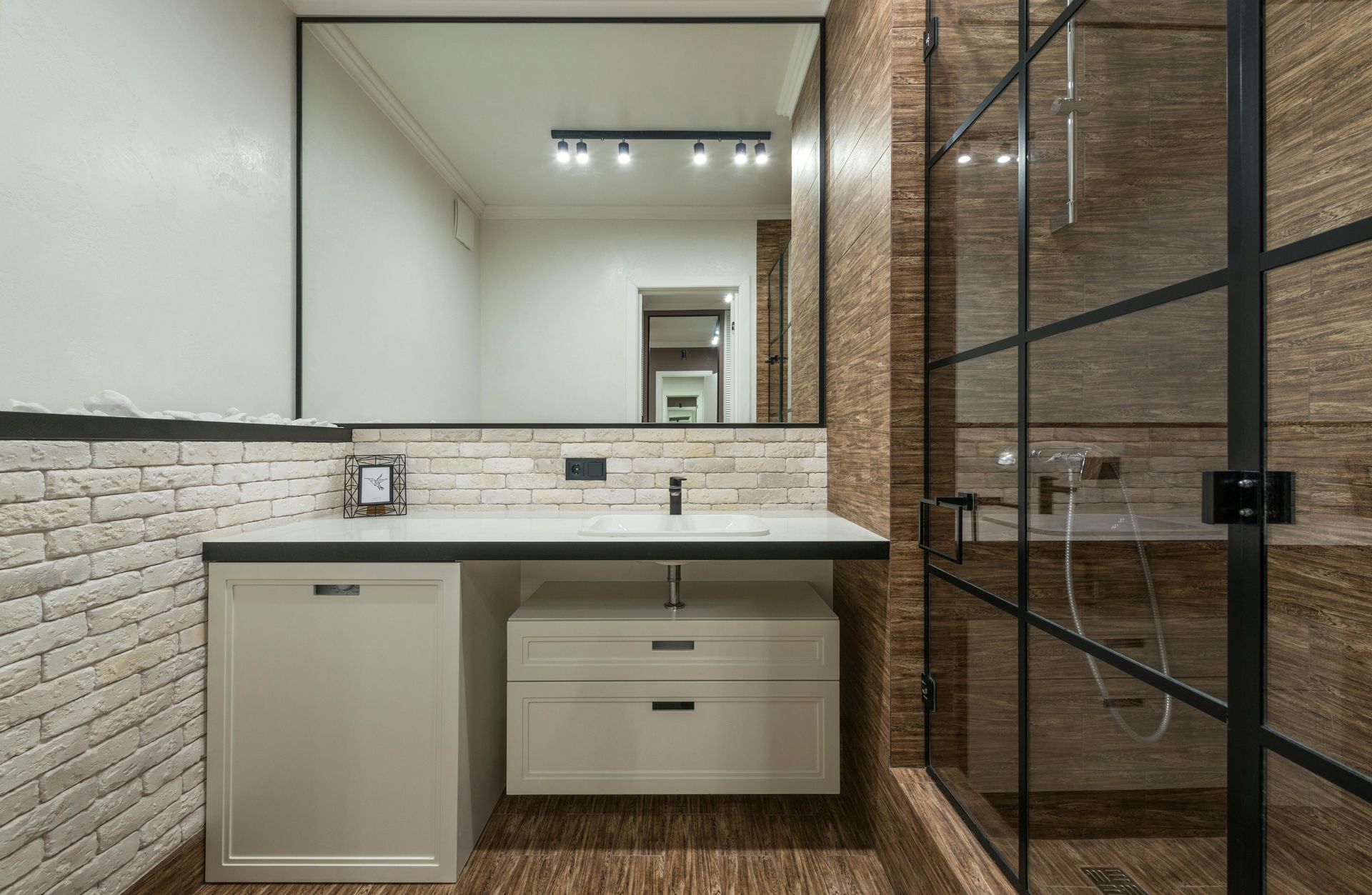A bathroom with a sink , mirror and walk in shower.