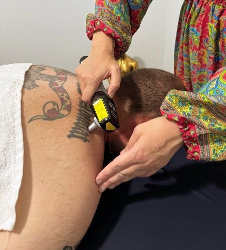 A Person Is Getting An Electrotherapy Treatment On Their back — Resonance Health Studio in Wauchope, NSW