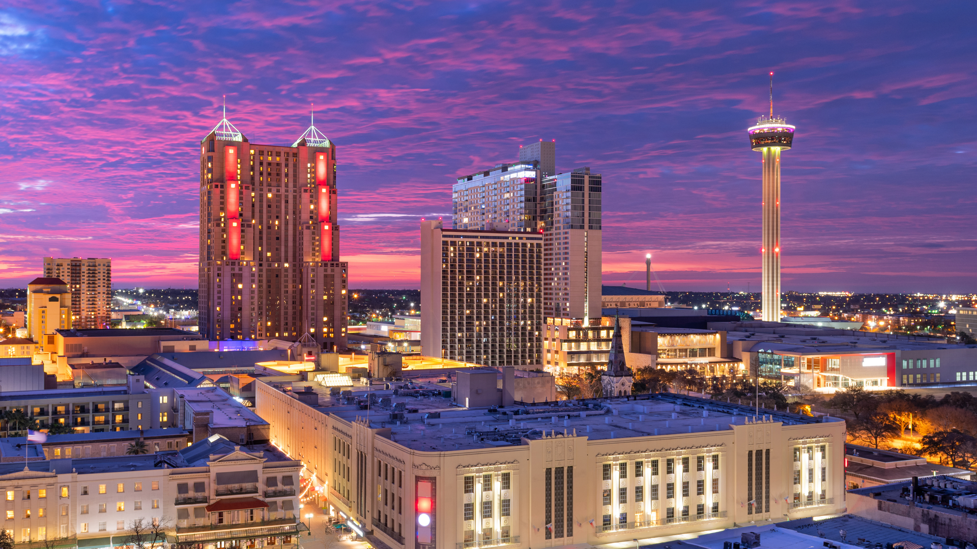 Austin, Texas skyline at dusk, with buildings of various heights and a bridge over a river.