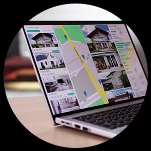 Laptop screen displaying a real estate website, showing houses for sale and a map.