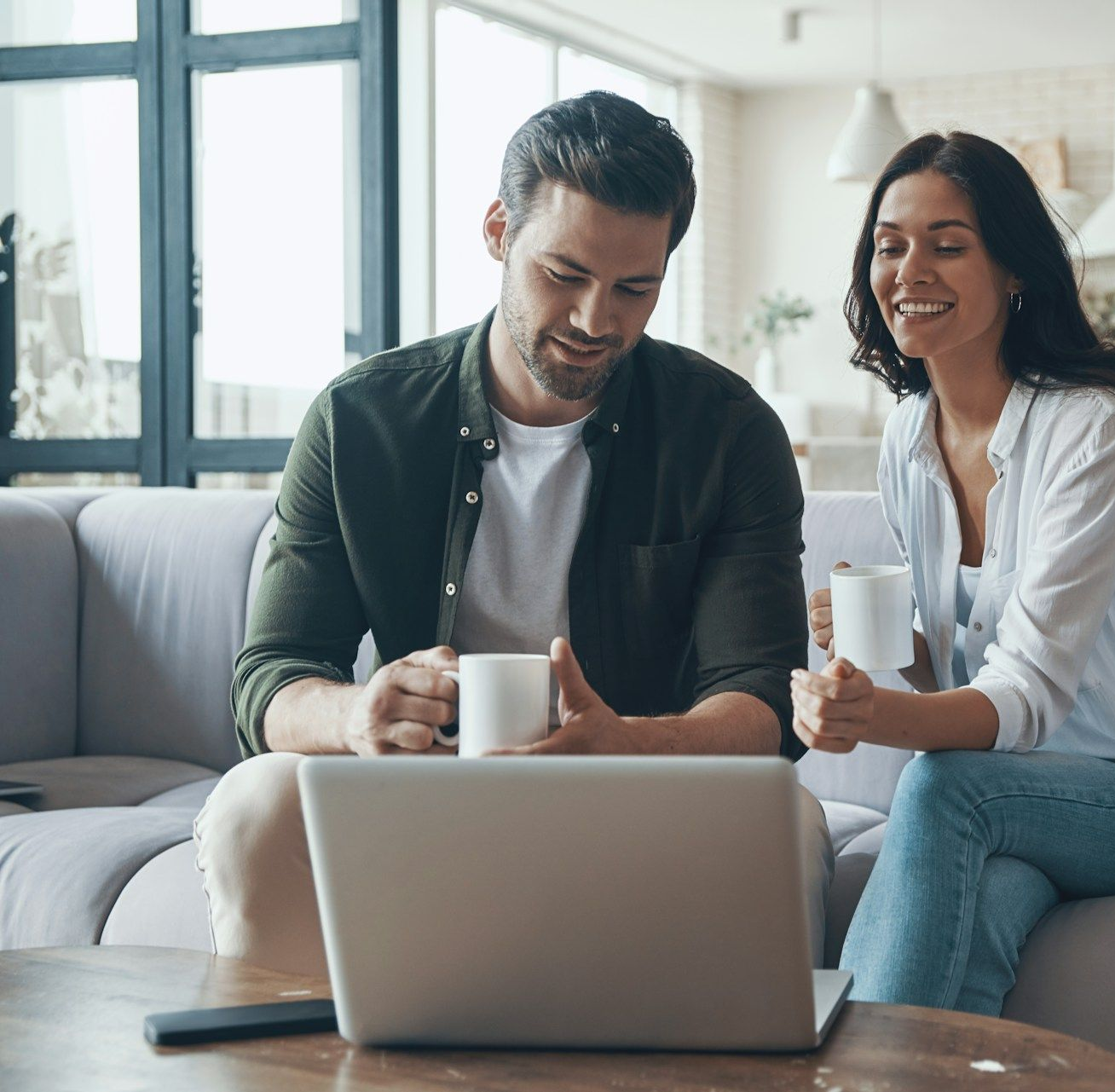 Woman in glasses on the phone, smiling, looking at papers, wearing a patterned blazer.