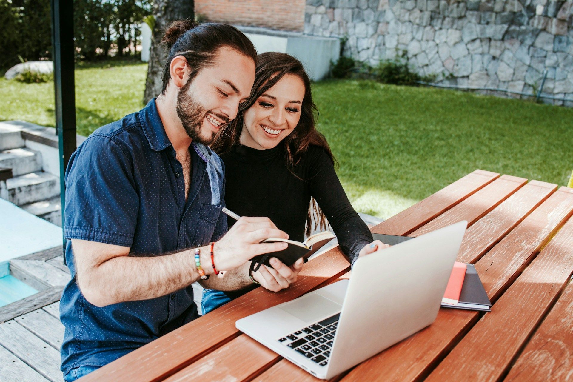 Woman in glasses on the phone, smiling, looking at papers, wearing a patterned blazer.