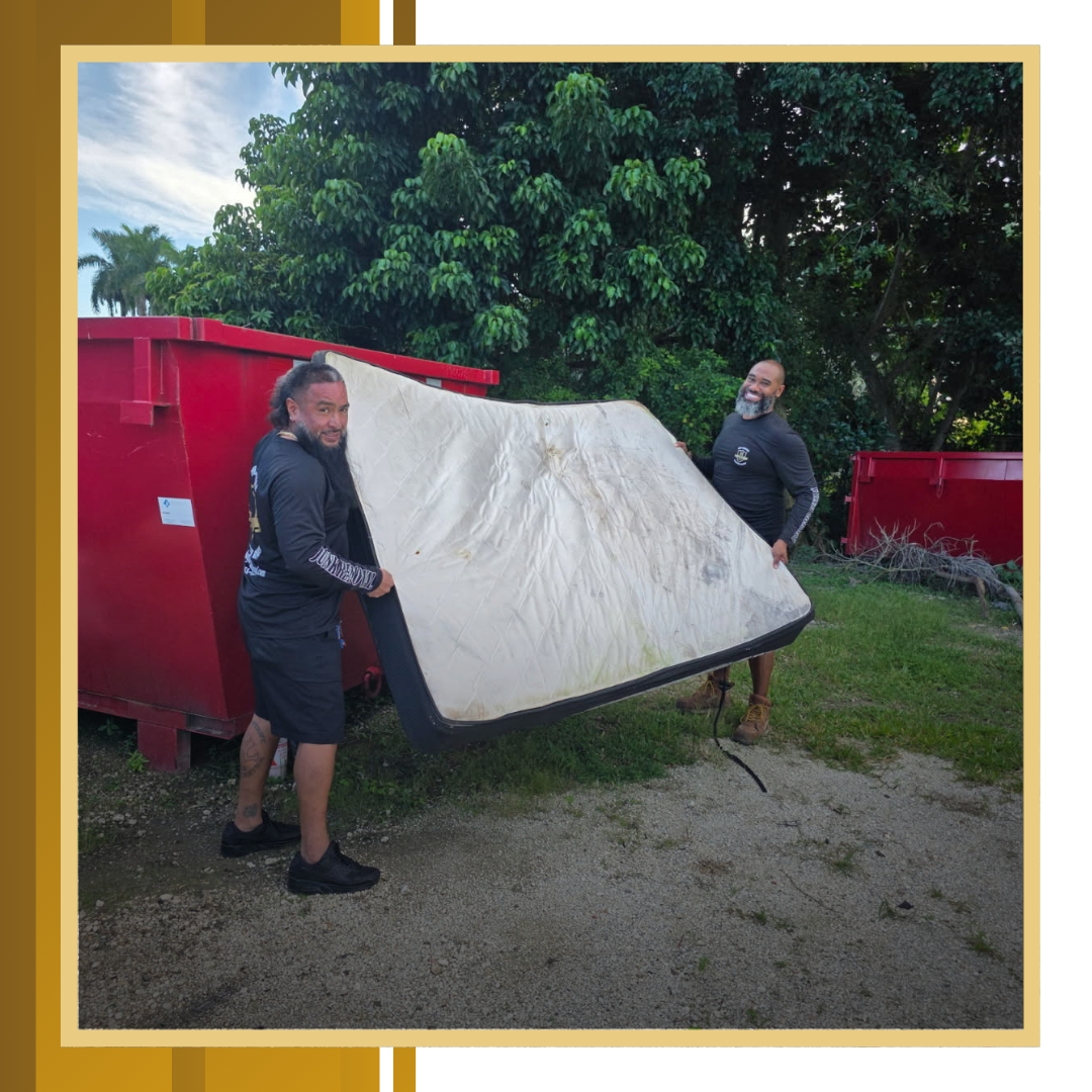 Old mattress with two men standing and holding it.