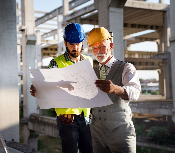 Two construction workers are looking at a blueprint on a construction site. Two construction workers are looking at a blueprint on a construction site.