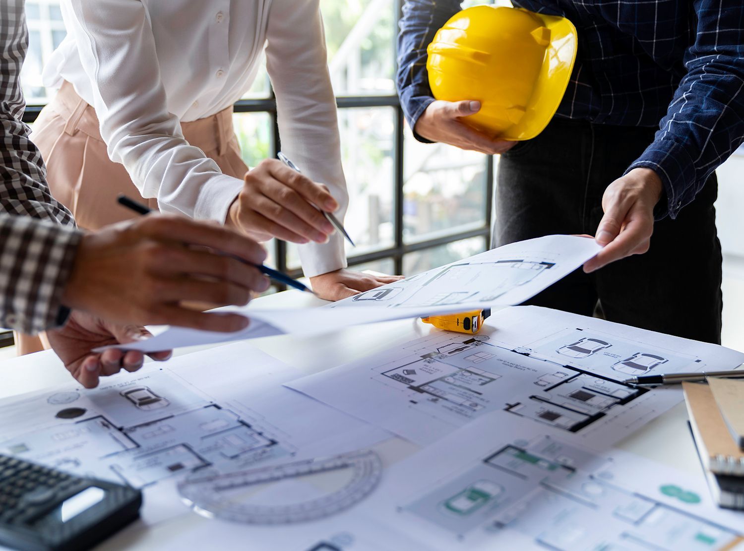A group of people are looking at a blueprint on a table. A group of people are looking at a blueprint on a table.