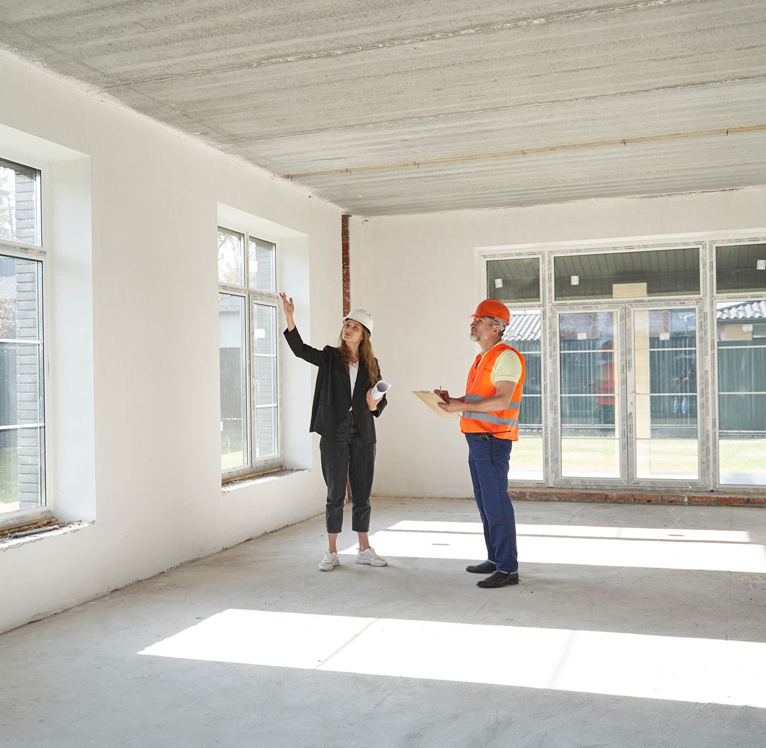 A man and a woman are standing in an empty room looking at a window. A man and a woman are standing in an empty room looking at a window.
