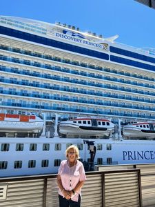 Woman standing by a large Princess cruise ship docked at port.