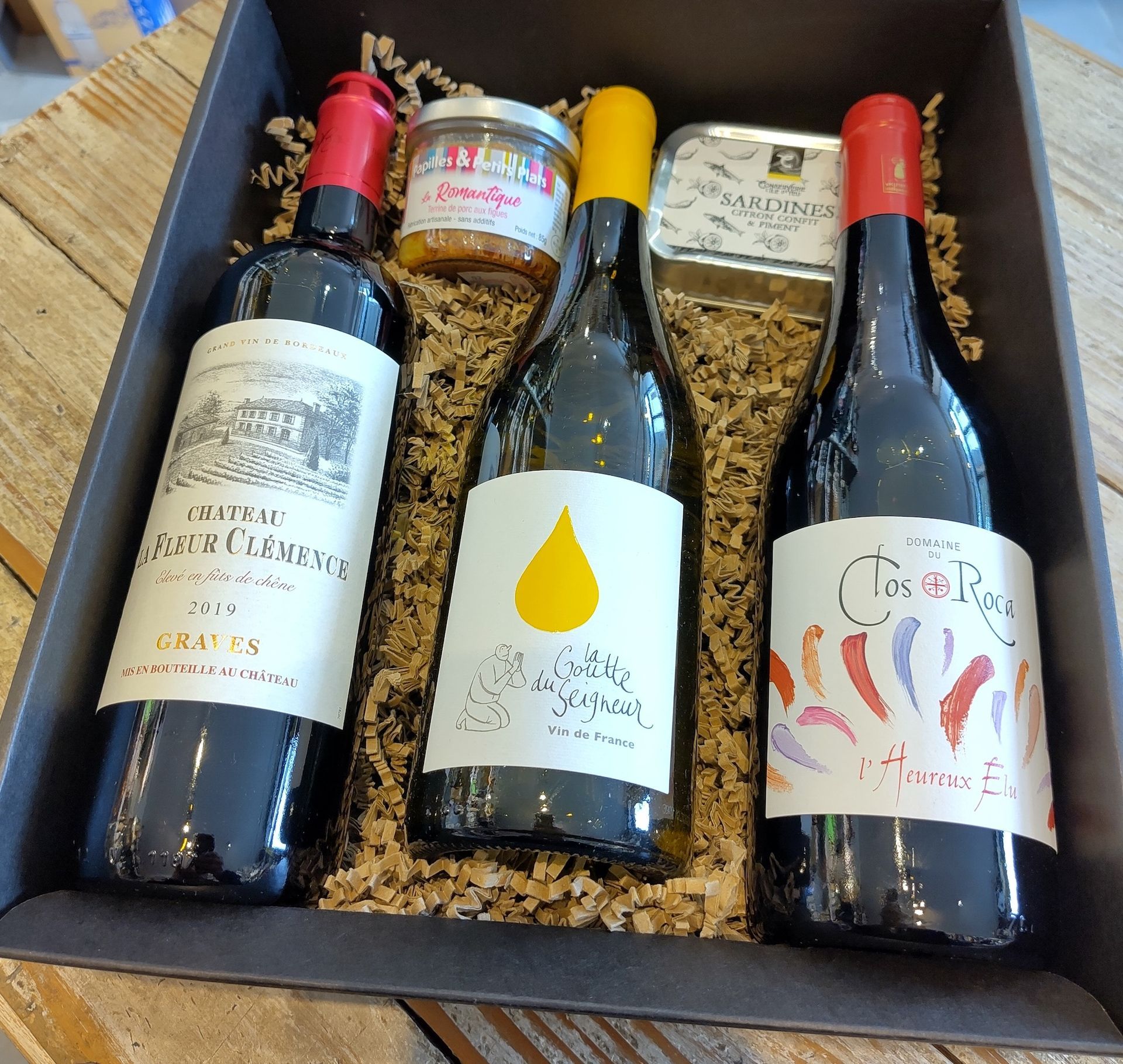 Quatre bouteilles de vin sont dans une boîte sur une table en bois