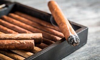 Burning Cigar With Smoke On Wooden Humidor — Liquor Store in Redmond, WA