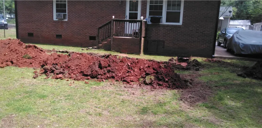A large pile of dirt is in front of a brick house.
