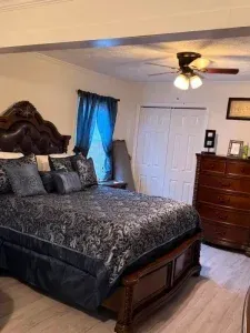 A bedroom with a bed , dresser , and ceiling fan.