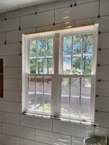 A window in a bathroom with white tiles on the wall.