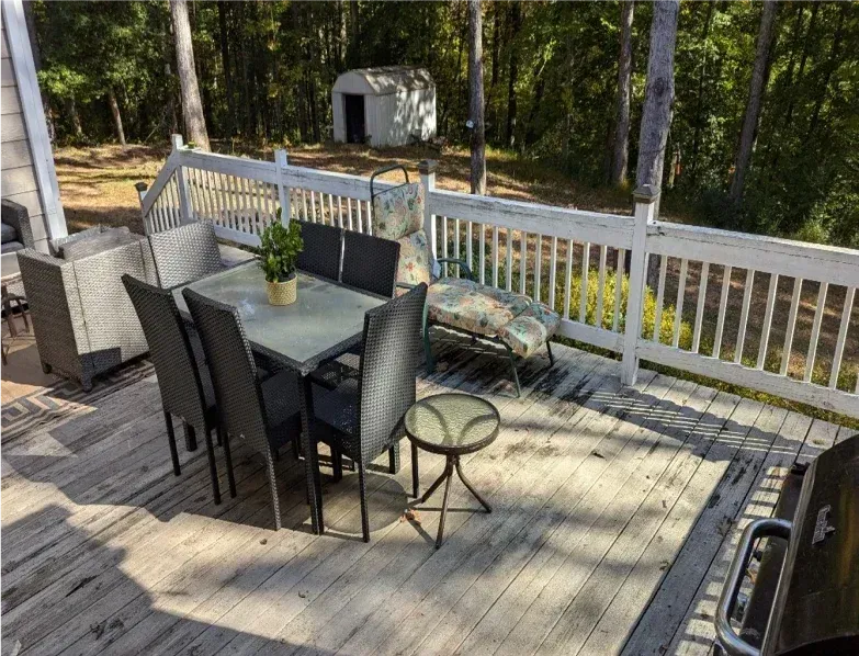 A deck with a table and chairs and a grill.
