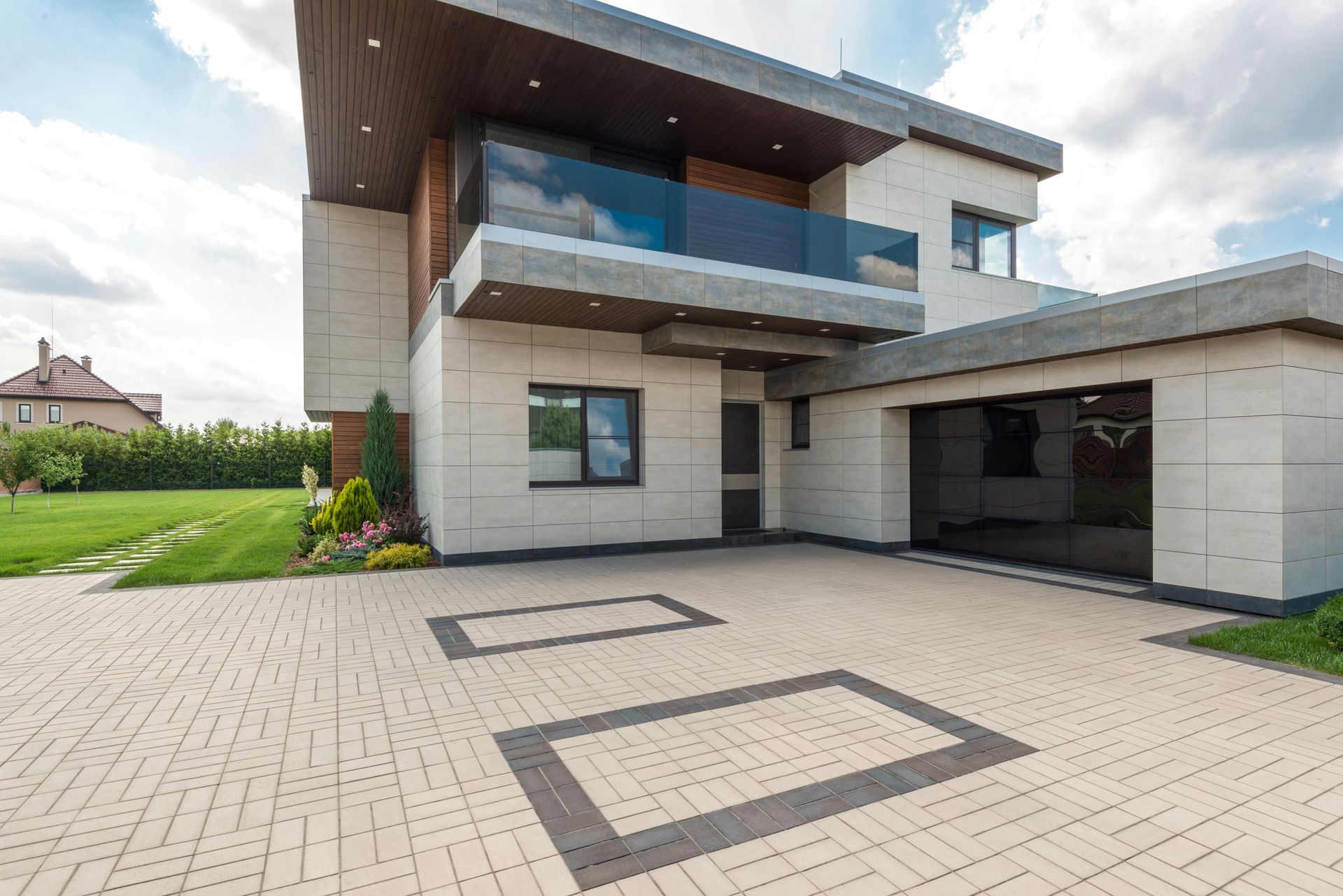 A large modern house with a large driveway in front of it.
