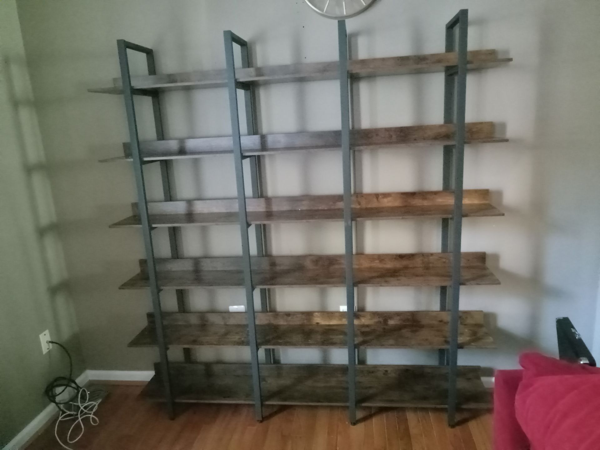 A bookshelf is sitting in a living room next to a couch.