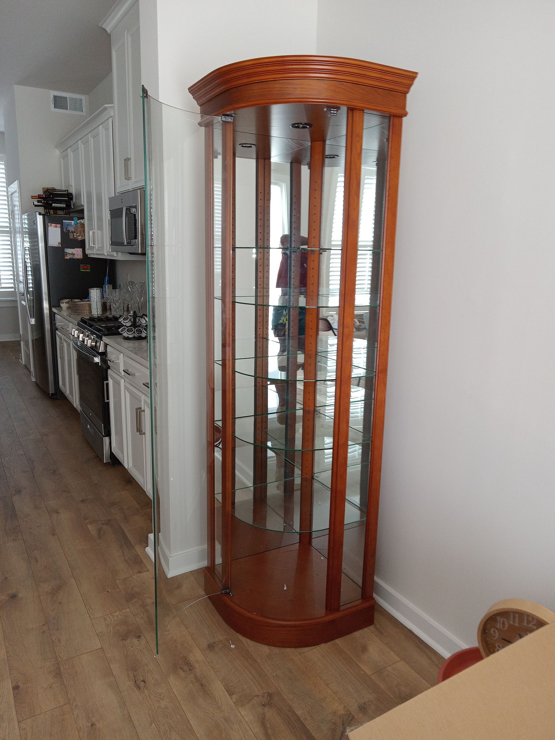 A wooden display case is in the corner of a kitchen