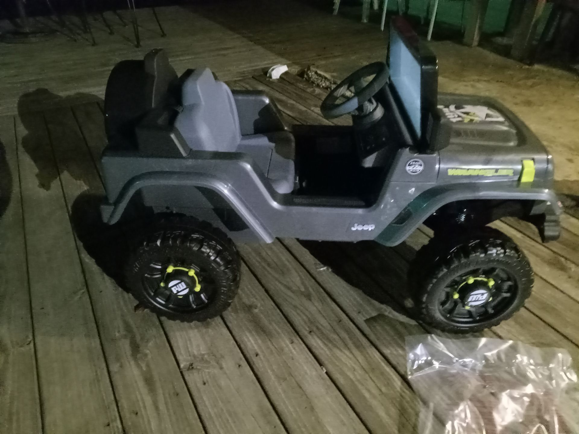 A toy jeep is sitting on a wooden deck.