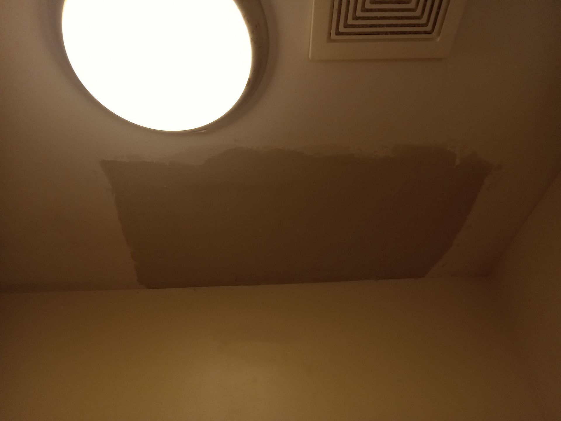 A light is shining through a hole in the ceiling of a room.