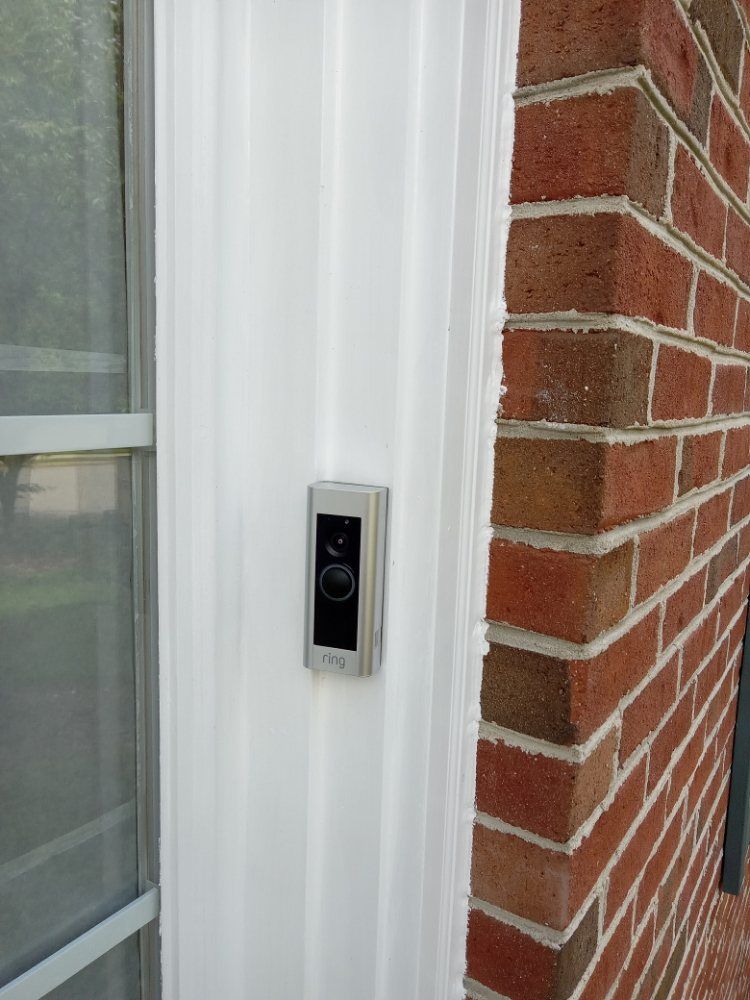 A doorbell is mounted on the side of a brick building.