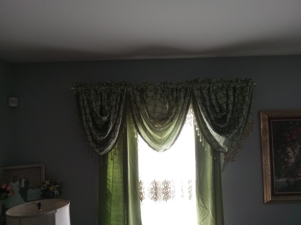 A living room with green curtains and a painting on the wall.