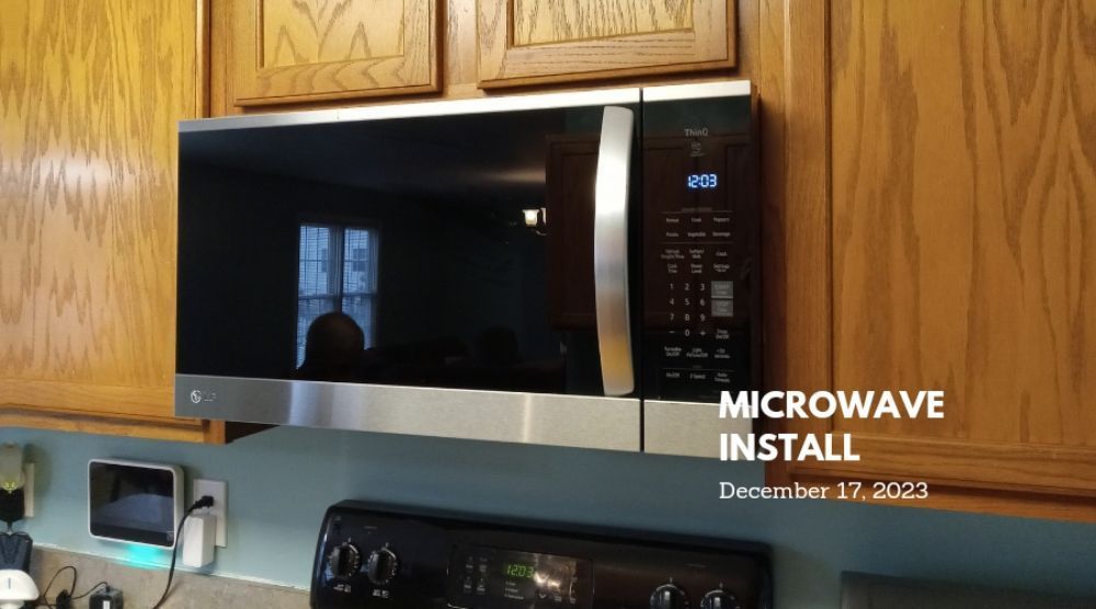 A microwave is being installed in a kitchen.