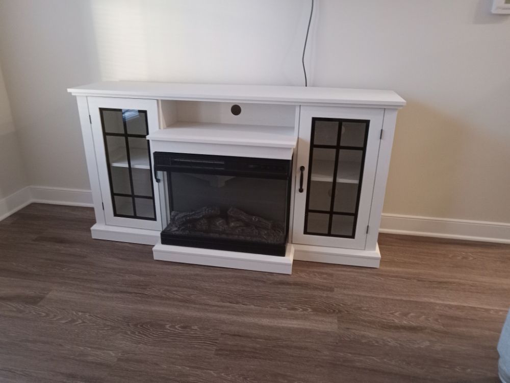 A white entertainment center with a fireplace underneath it