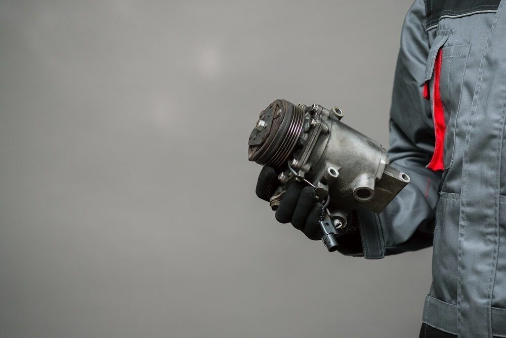 A Man Is Holding a Compressor in His Hands — Multidrive Parts Australia in Moree, NSW