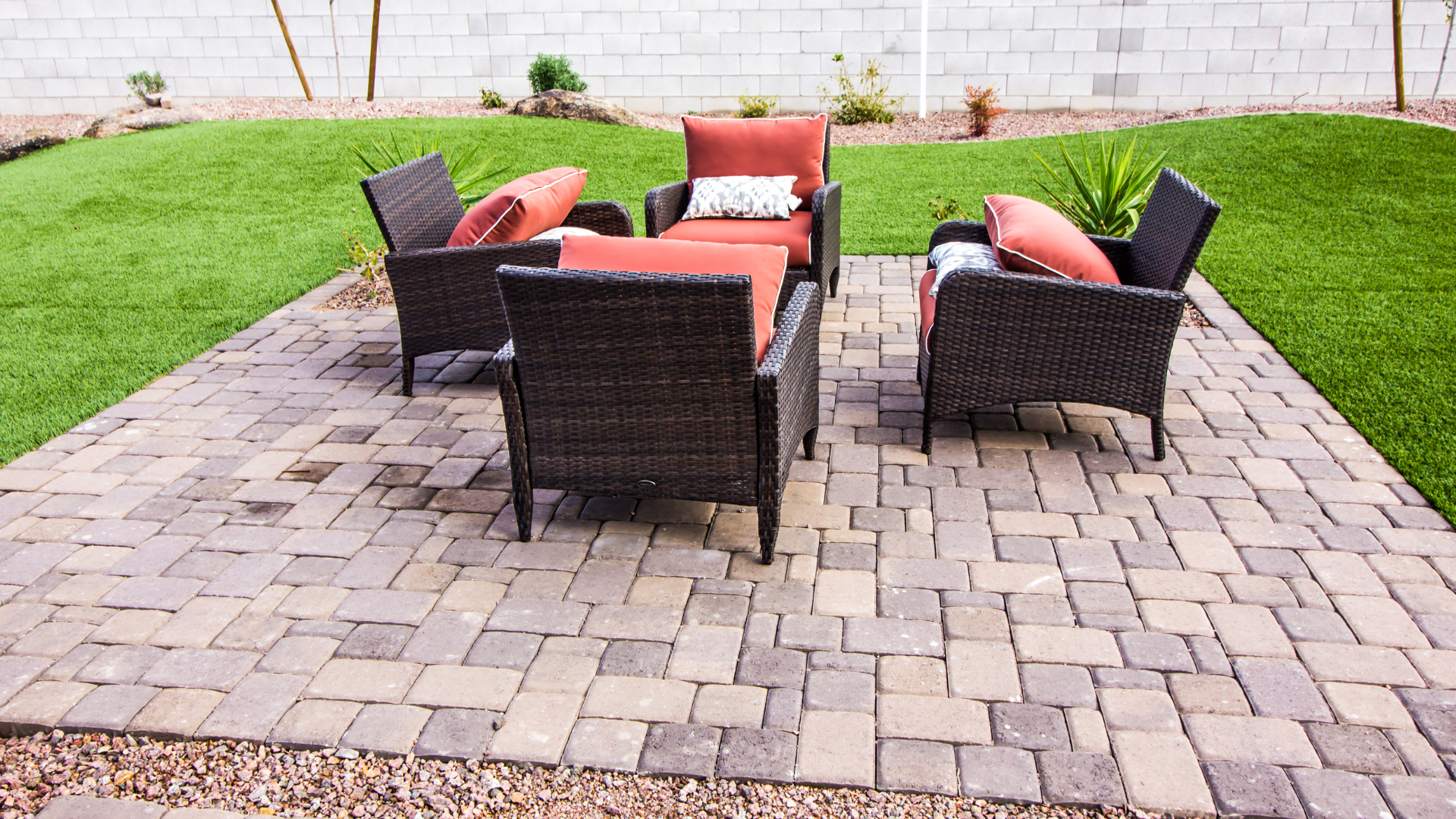 a patio with wicker furniture and a lawn in the background .