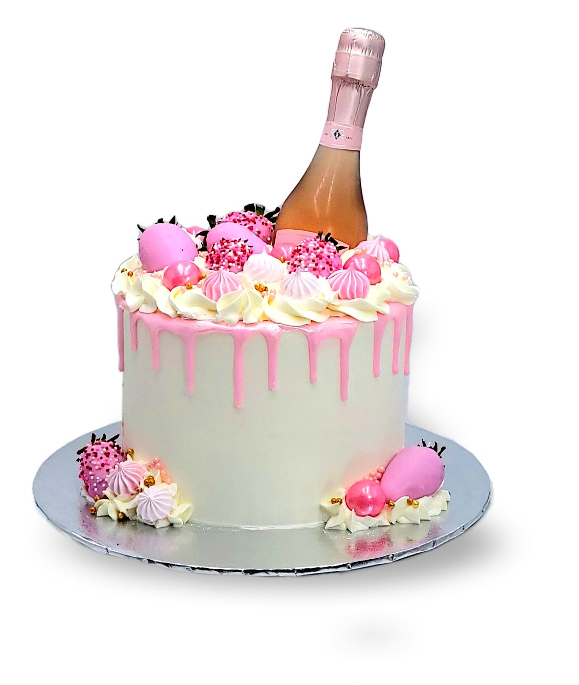A white cake with pink drips, topped with pink-dipped strawberries, meringues, and a small bottle of rosé champagne.