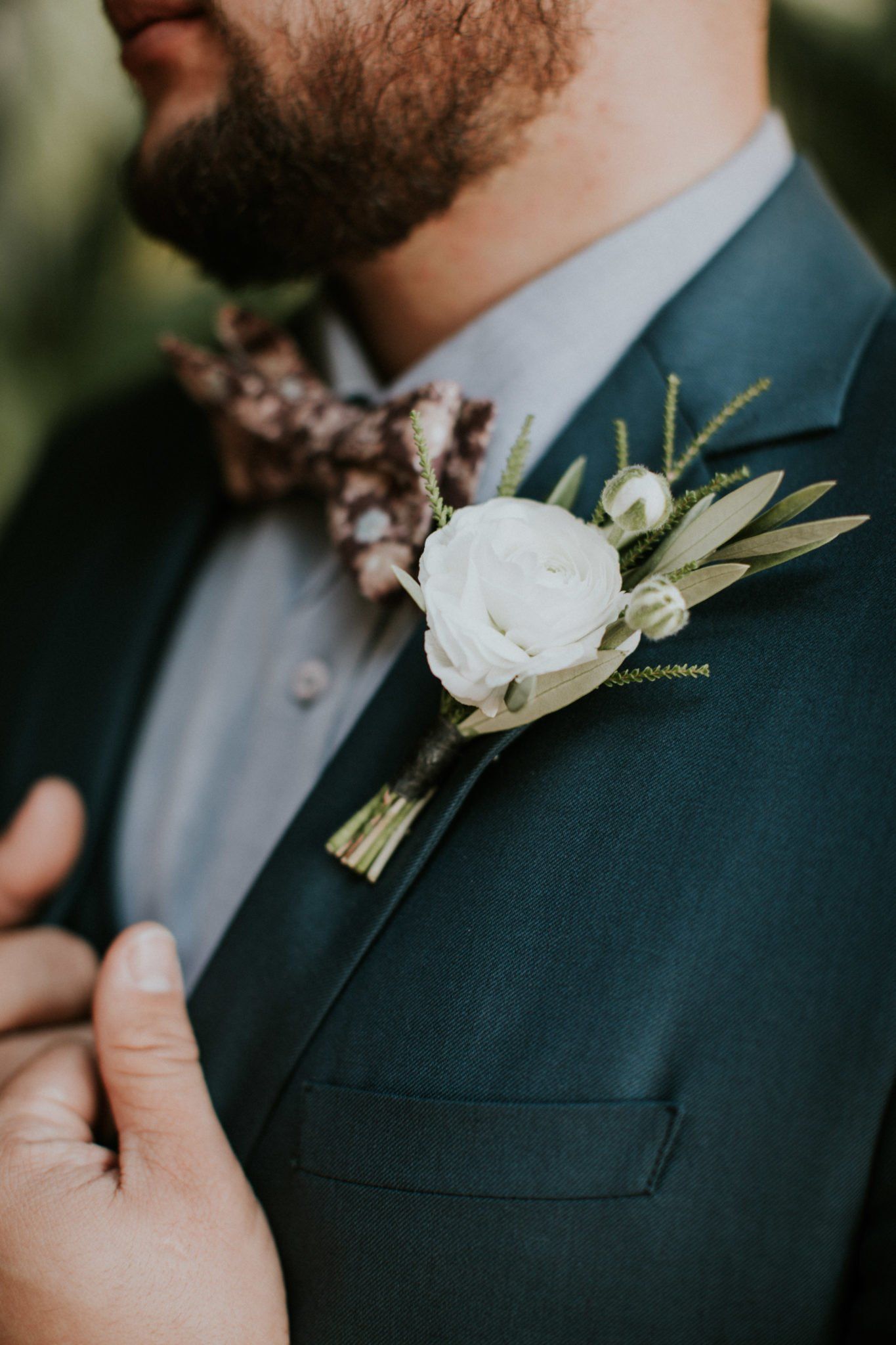 A man in a suit and bow tie has a flower on his jacket.